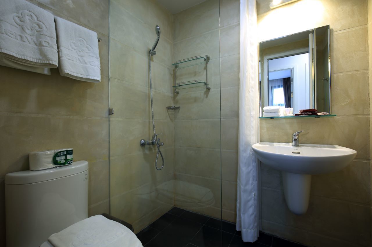 A bathroom with a glass shower enclosure, a white sink, and a toilet.
