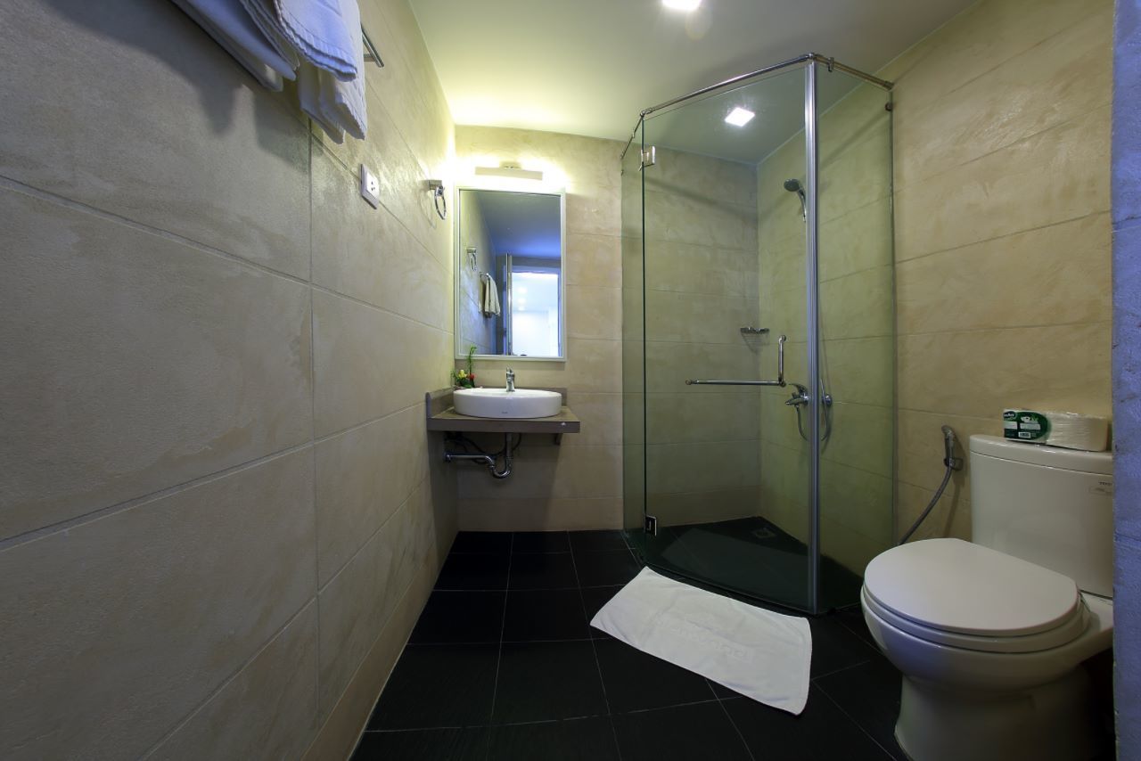 A bathroom with a glass-enclosed shower, a sink with a mirror, and a toilet.
