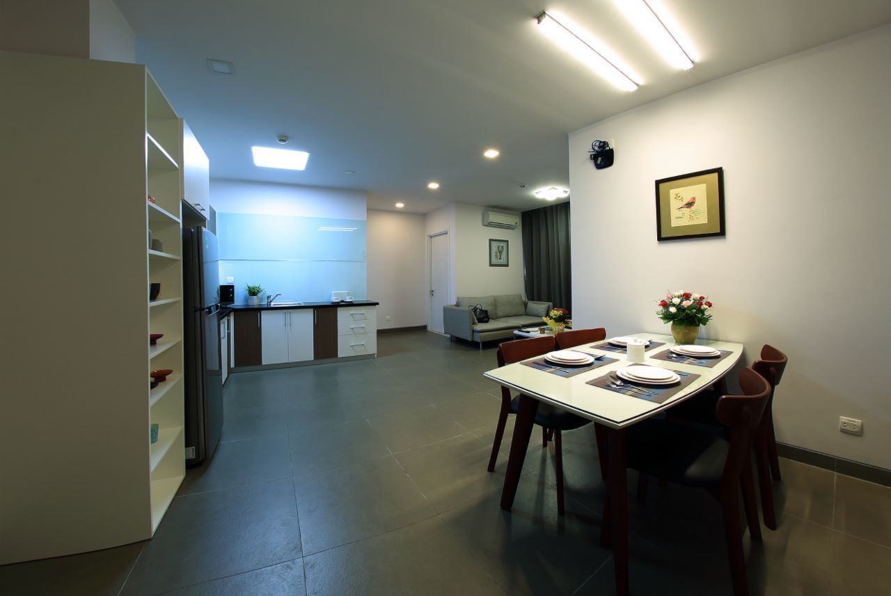A modern kitchen with white cabinets, a built-in refrigerator, and a dining area with a table set for four.