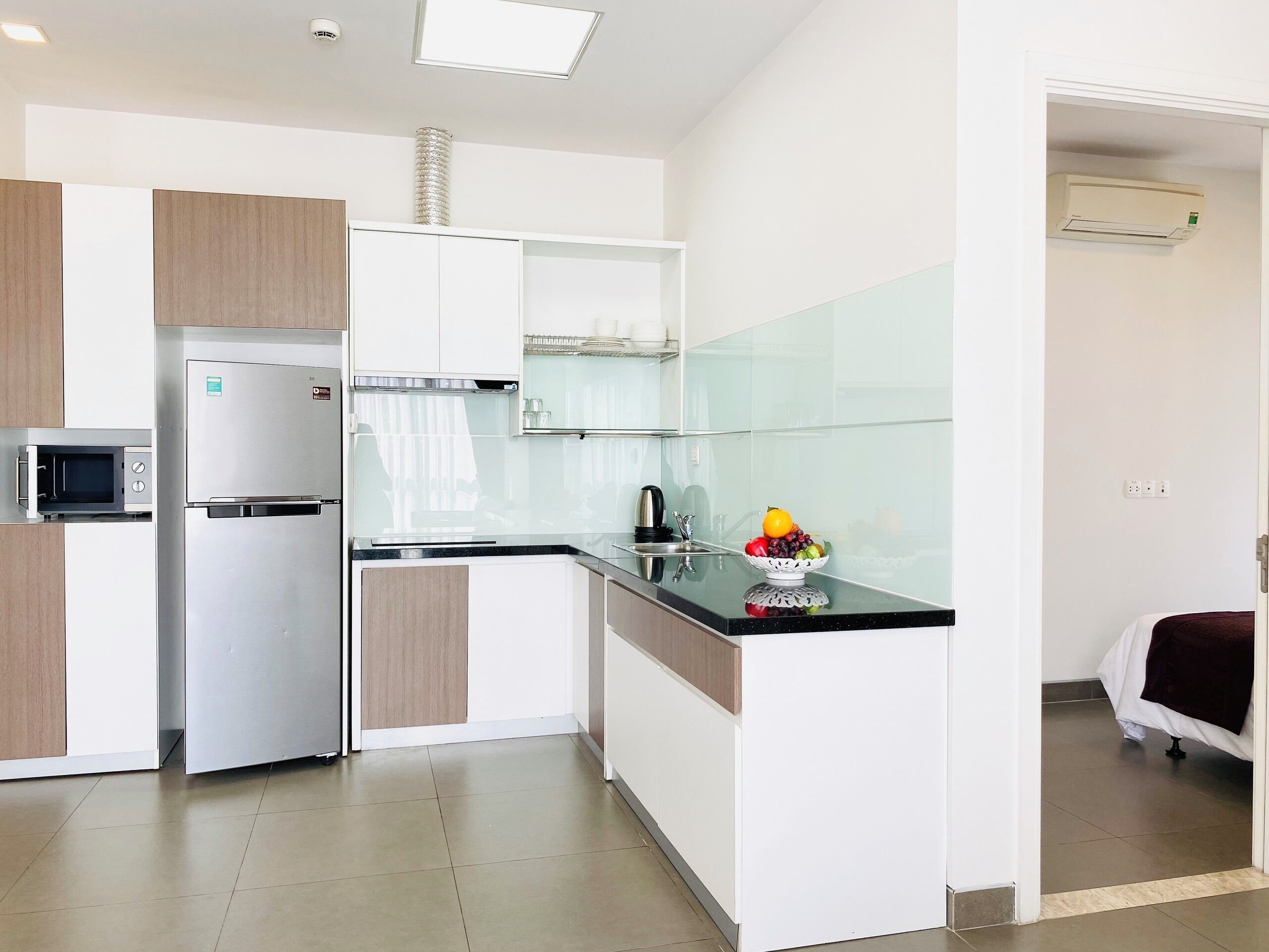 A modern kitchen with a built-in microwave, stainless steel refrigerator, and a glass-top island.