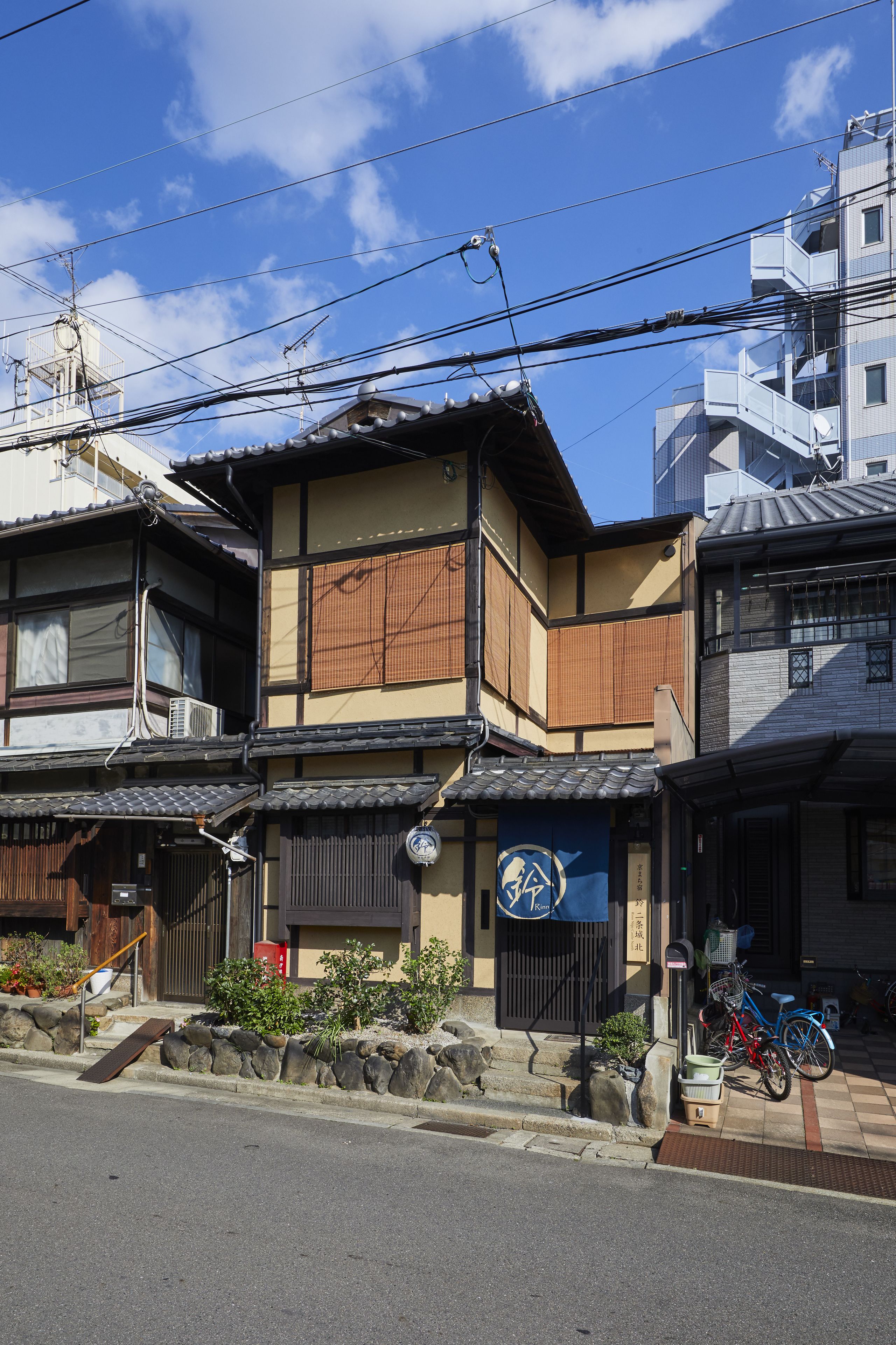 A traditional Japanese building with a wooden exterior, a tiled roof, and a small garden area with rocks and plants.