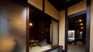 A traditional Japanese room with tatami flooring, a low table with cushions, and a sliding door. - Rinn Premium Machiya Townhouse Kyoto Nijo Castle North (Kyoto)
