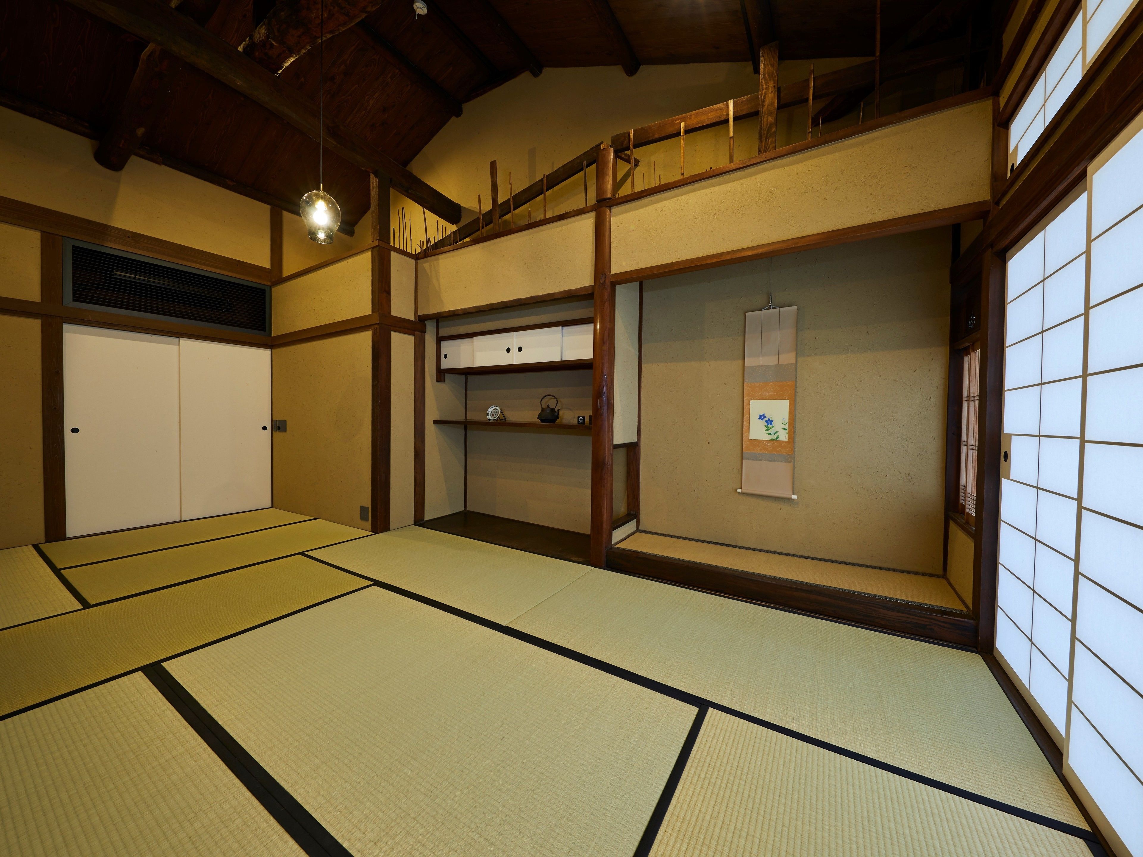 A traditional Japanese room with tatami flooring, a sliding door, and a shelf with decorative items.