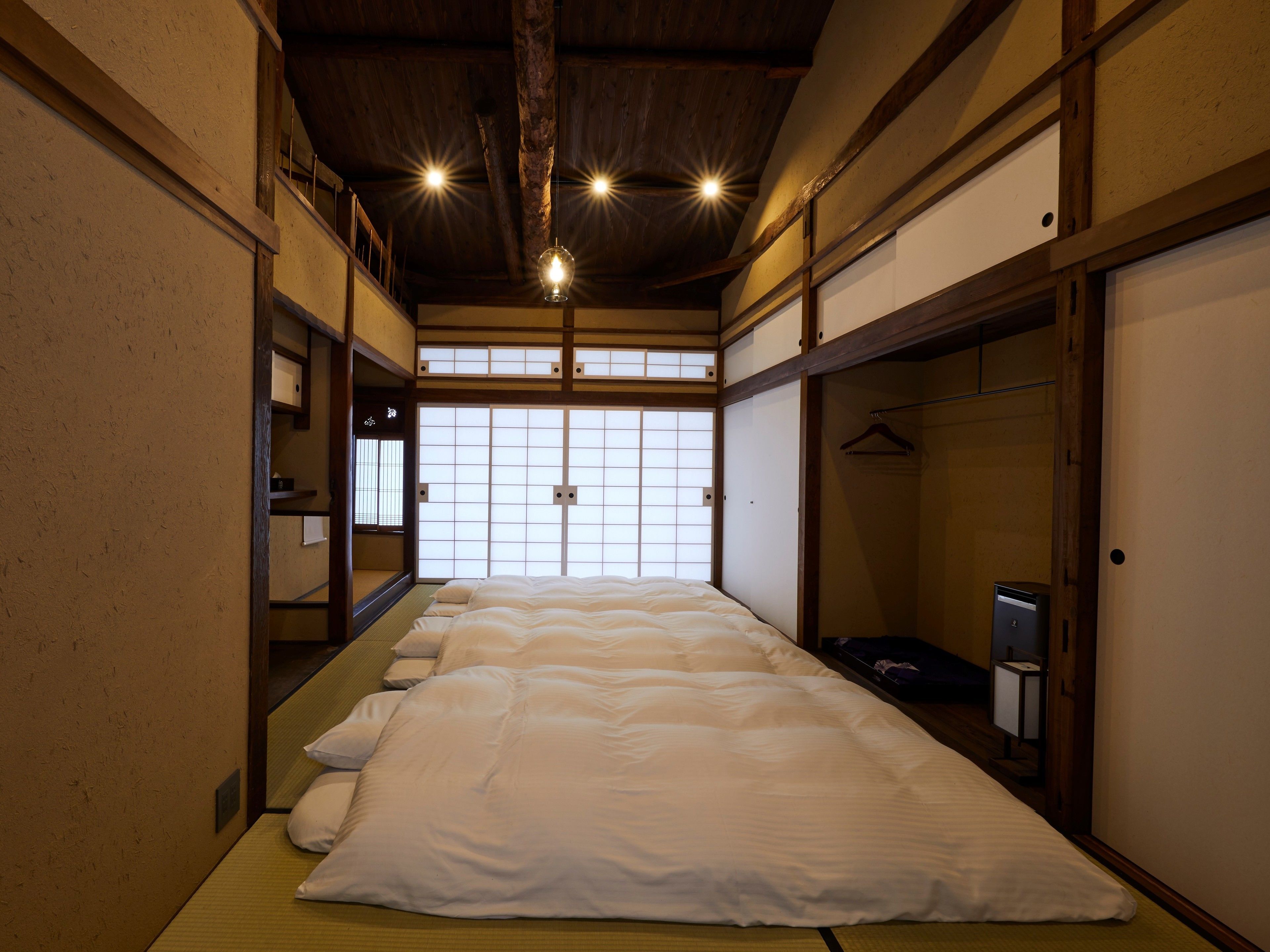 A traditional Japanese-style room with tatami flooring, a low ceiling with exposed beams, and a sliding door leading to a wardrobe.