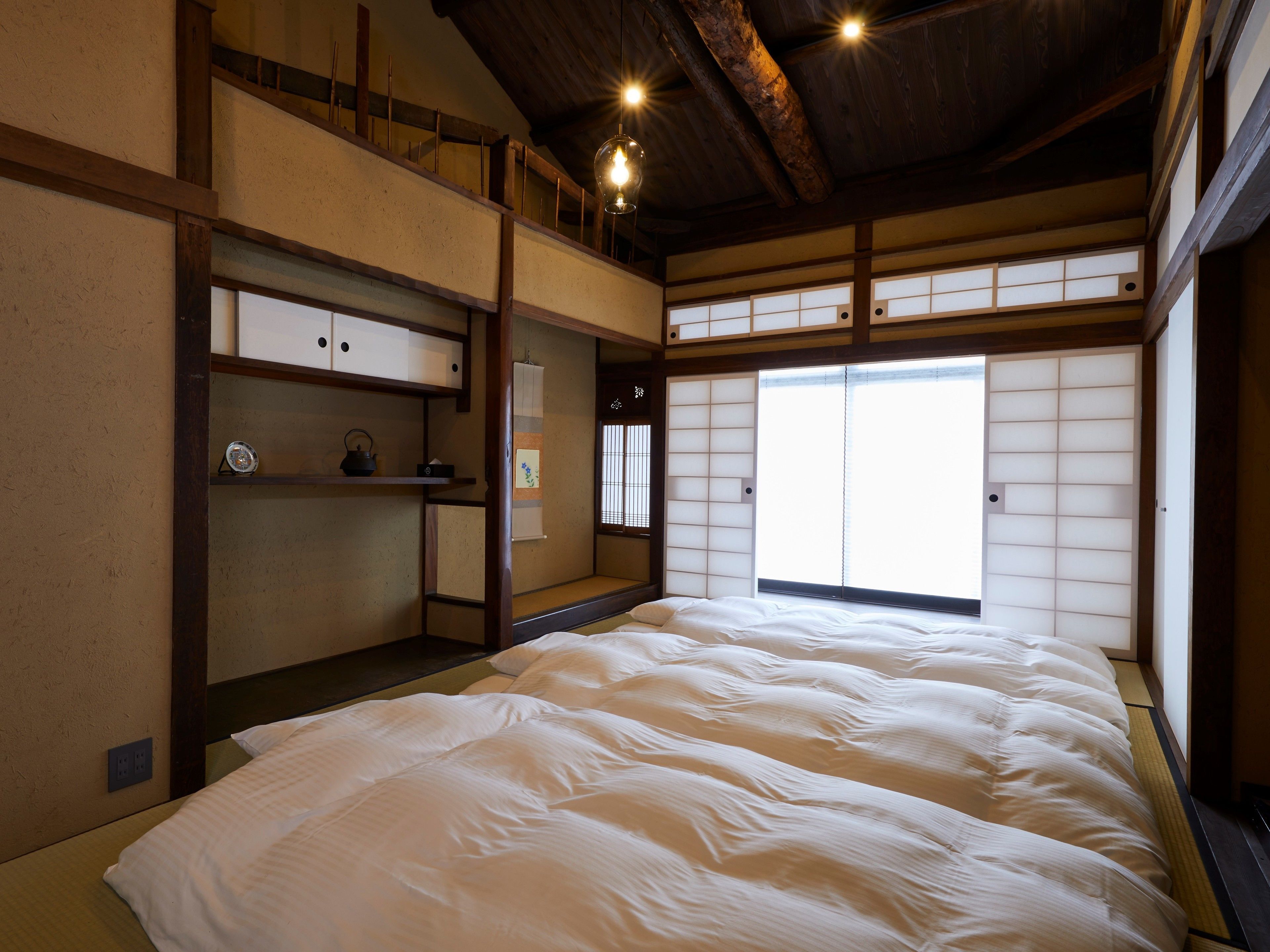 Um quarto tradicional em estilo japonês, com piso de tatame, cama futon, portas deslizantes shoji e teto de madeira.