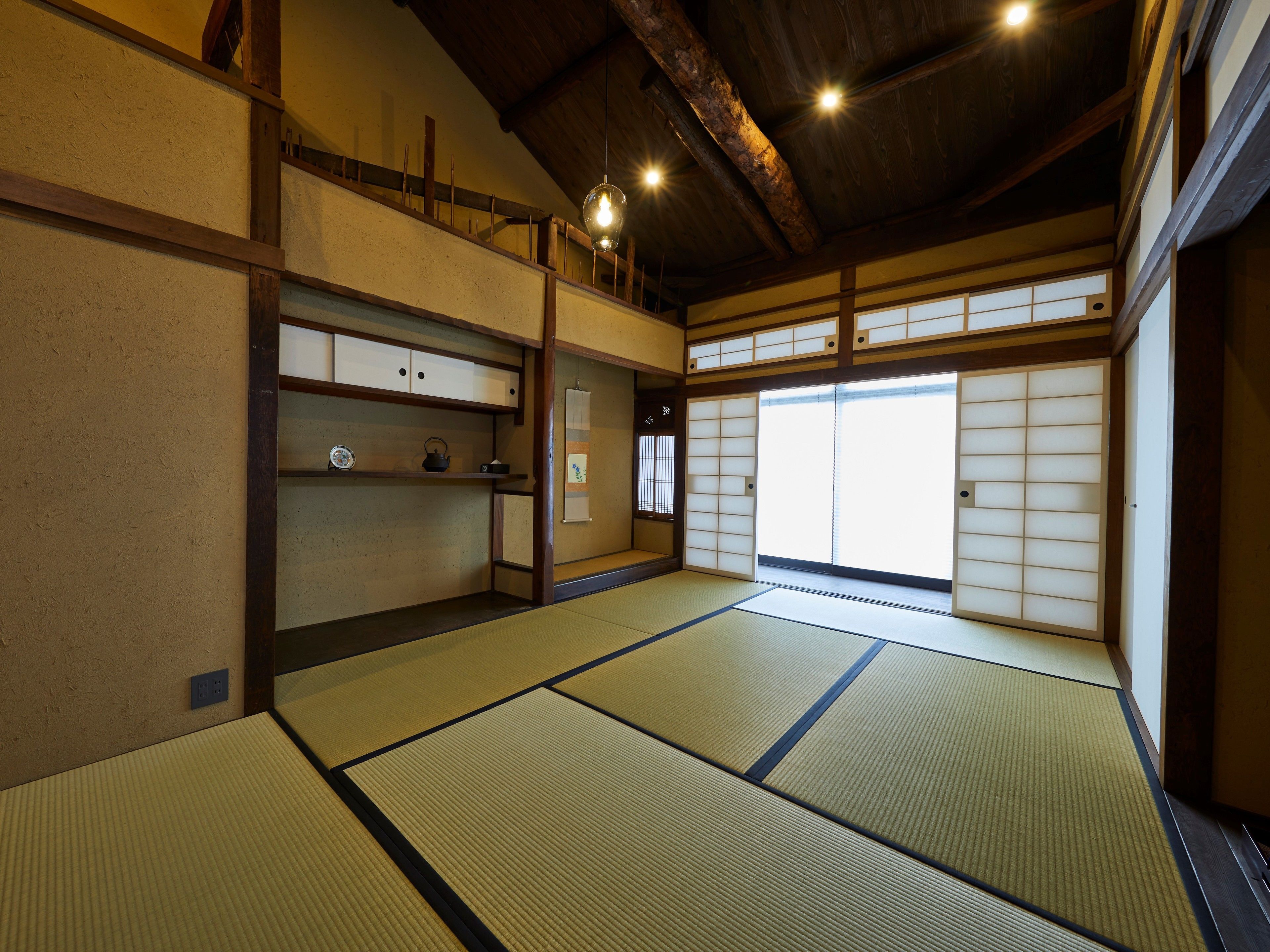 A traditional Japanese room with tatami flooring, sliding doors, and a wooden ceiling.