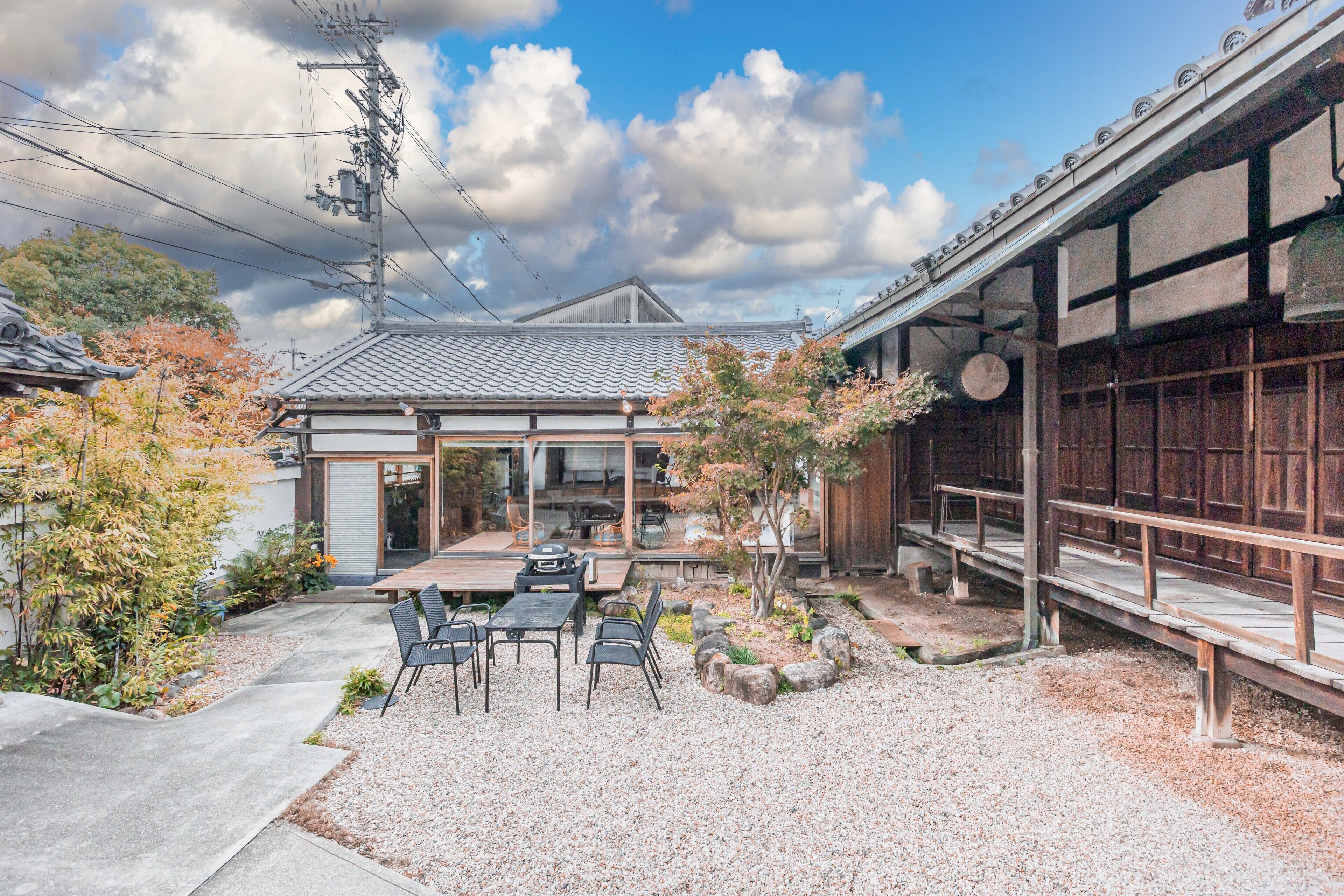 A traditional Japanese-style building with a covered patio, outdoor seating, and a gravel garden.