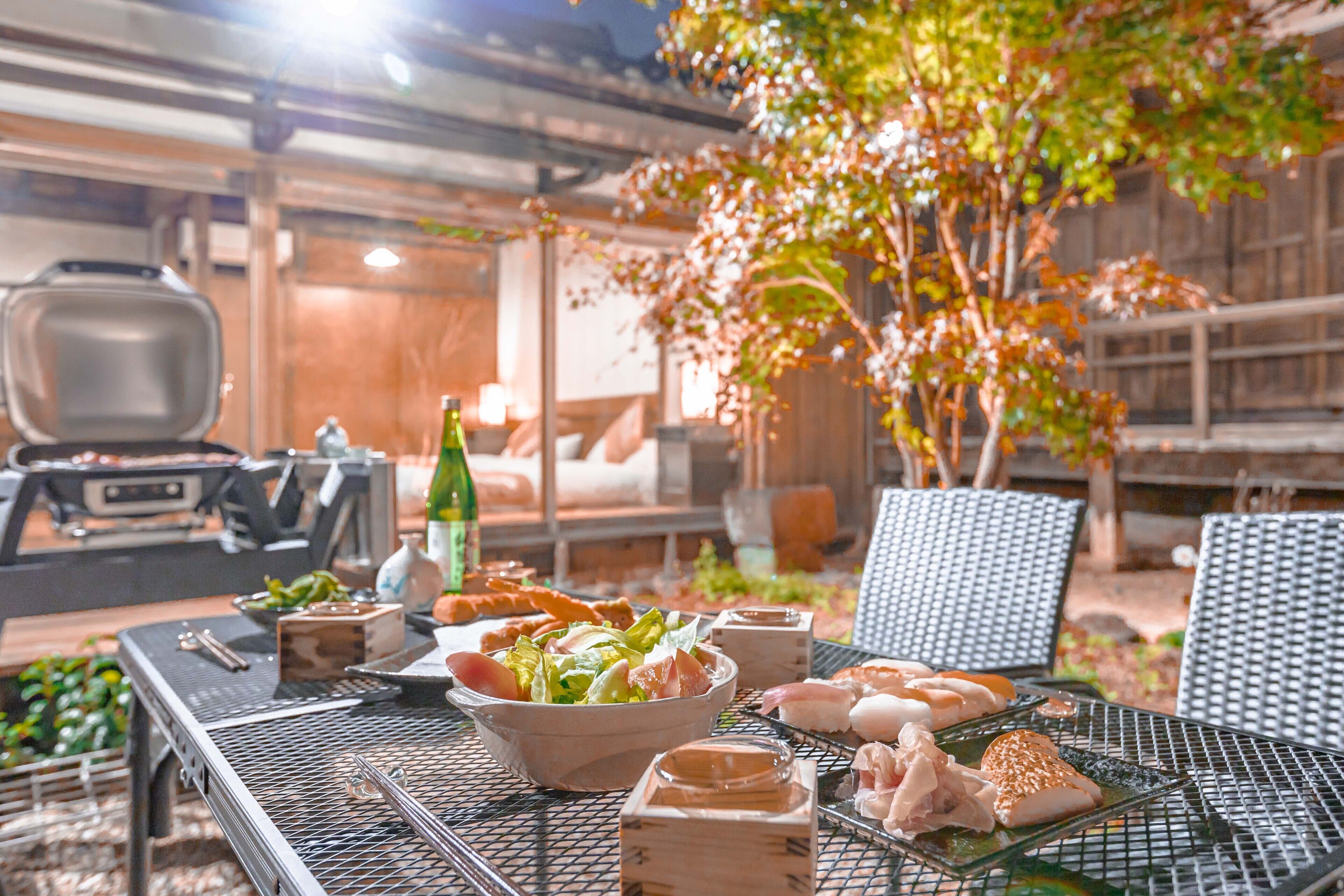 Een terras met een barbecue, zitplaatsen en diverse gerechten.