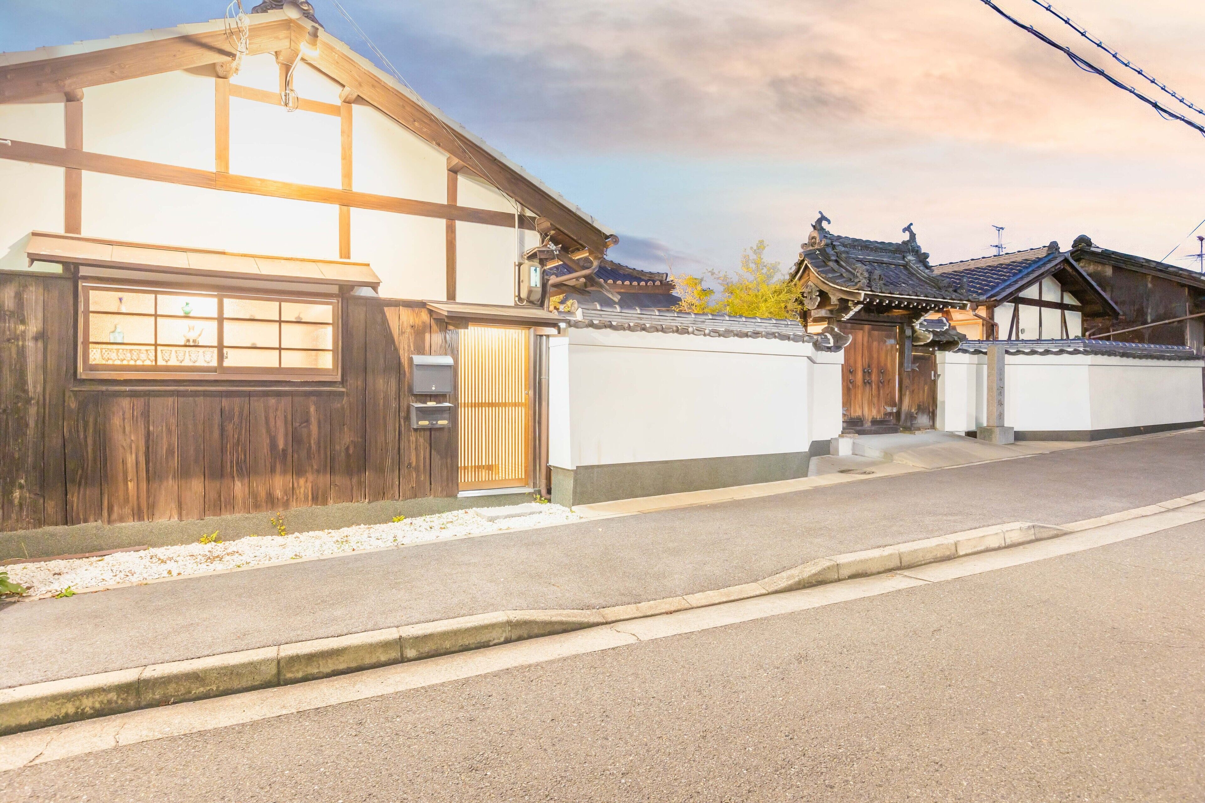 A traditional Japanese house with a wooden exterior, a tiled roof, and a small garden area.