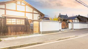 A traditional Japanese house with a wooden exterior, a tiled roof, and a small garden area.