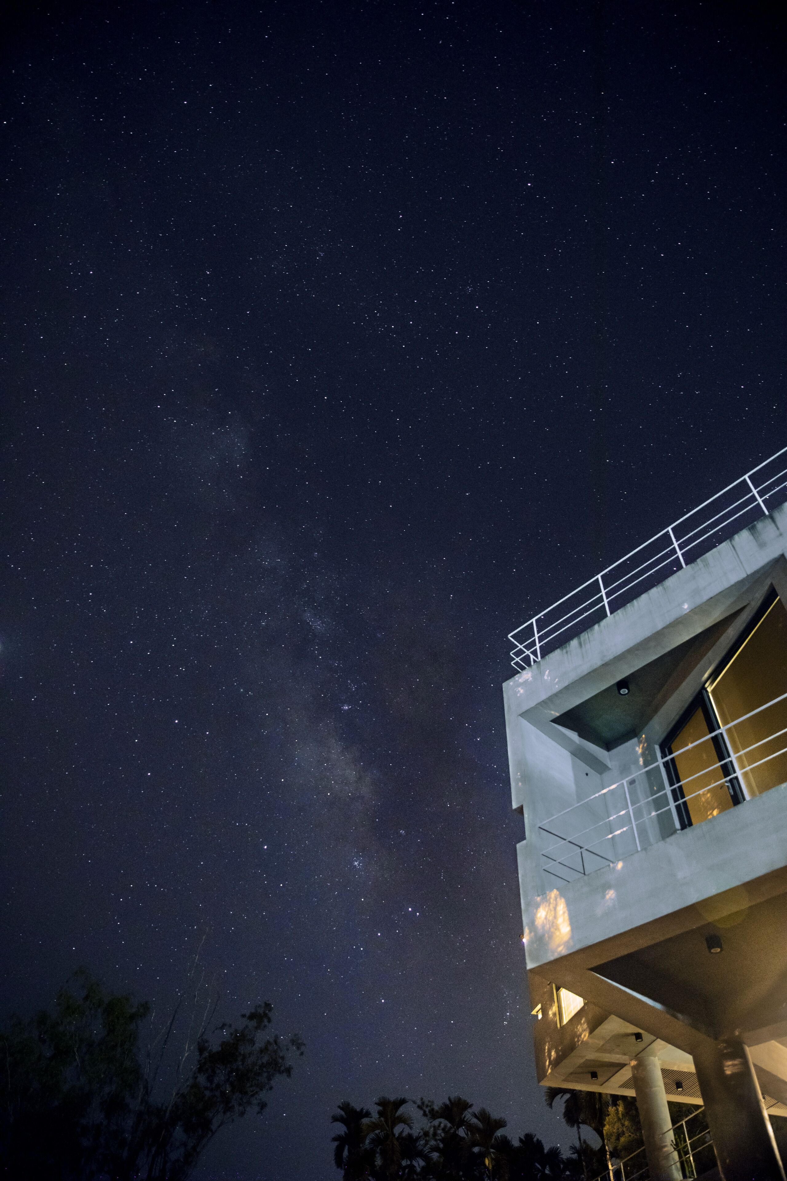 Un edificio moderno con un balcón bajo un cielo estrellado.