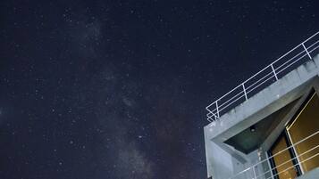 Un edificio moderno con un balcón bajo un cielo estrellado.
