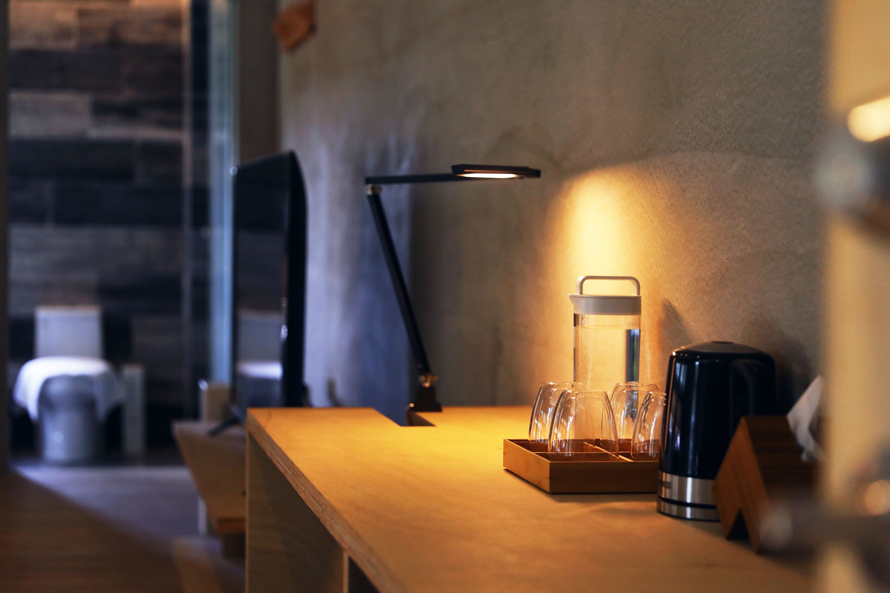 A wooden table with a coffee maker, a glass carafe, and a tray of glasses.