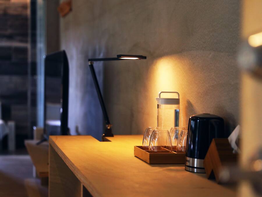 A wooden table with a coffee maker, a glass carafe, and a tray of glasses.