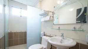 Une salle de bain équipée de toilettes, d’un lavabo et d’une douche à parois en verre.