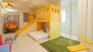 Une chambre d’enfant avec un lit superposé, un fauteuil suspendu, un jouet en forme de zèbre et un portique avec des balançoires.