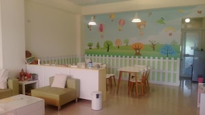 Une pièce conçue pour les enfants, avec un espace de jeux, une clôture blanche et une fresque représentant des arbres et des animaux.