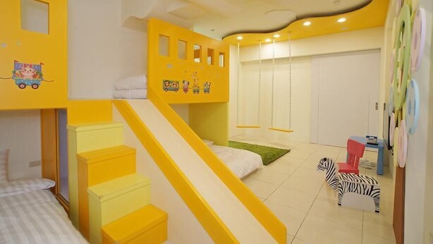 Une chambre d’enfant avec un lit superposé, un petit escalier, un espace de jeu avec un jouet en forme de zèbre et un placard avec une porte coulissante.