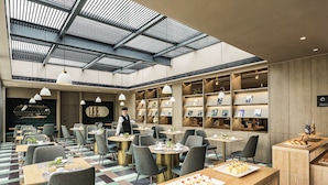 Ein modernes Restaurant mit hohen Decken und Oberlichtern, ein Kellner bedient Gäste.