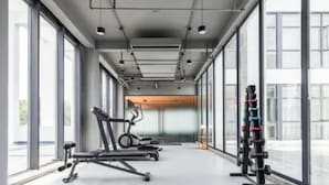 Ein modernes Fitnessstudio mit Laufbändern, Kraftgeräten und großen Fenstern mit Blick auf die Stadt.