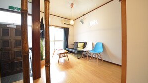 A room with a wooden floor, a sofa, a small table, and two chairs. - Private room ROSSO (Osaka)