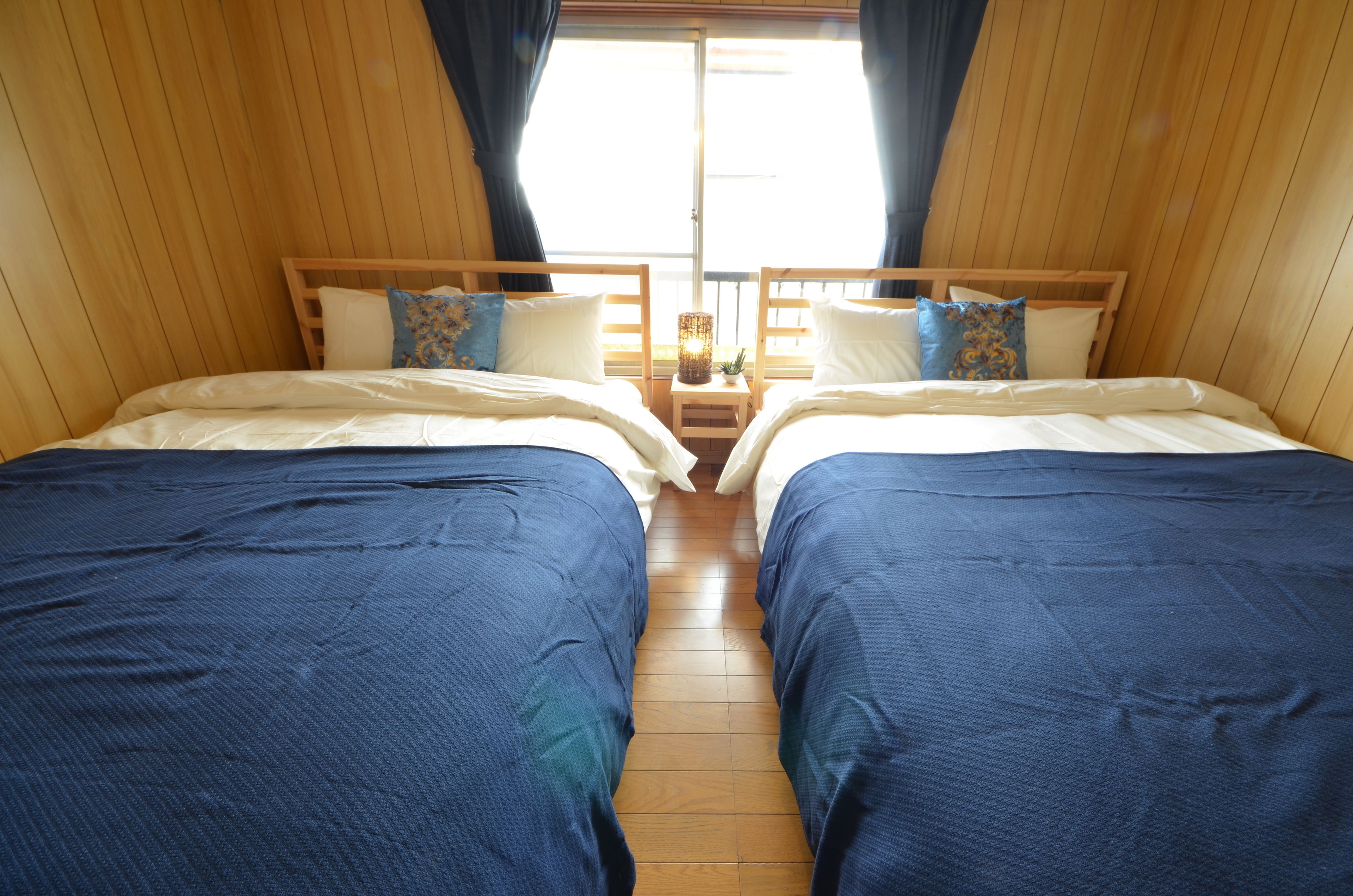 Une chambre avec deux lits, des murs en bois et une fenêtre avec des rideaux.