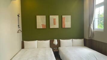A hotel room with two beds, a nightstand, a lamp, and three abstract paintings on the wall.