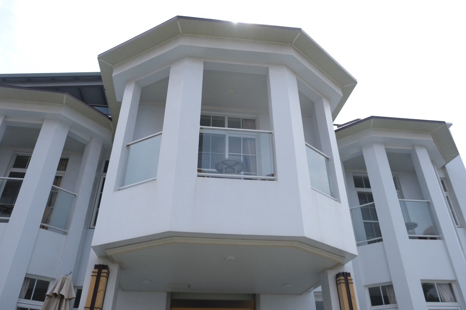 A corner bay window of a building with a white exterior and a balcony.