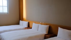 Habitación de hotel con dos camas individuales, cabeceros de madera, mesitas de noche y una ventana.
