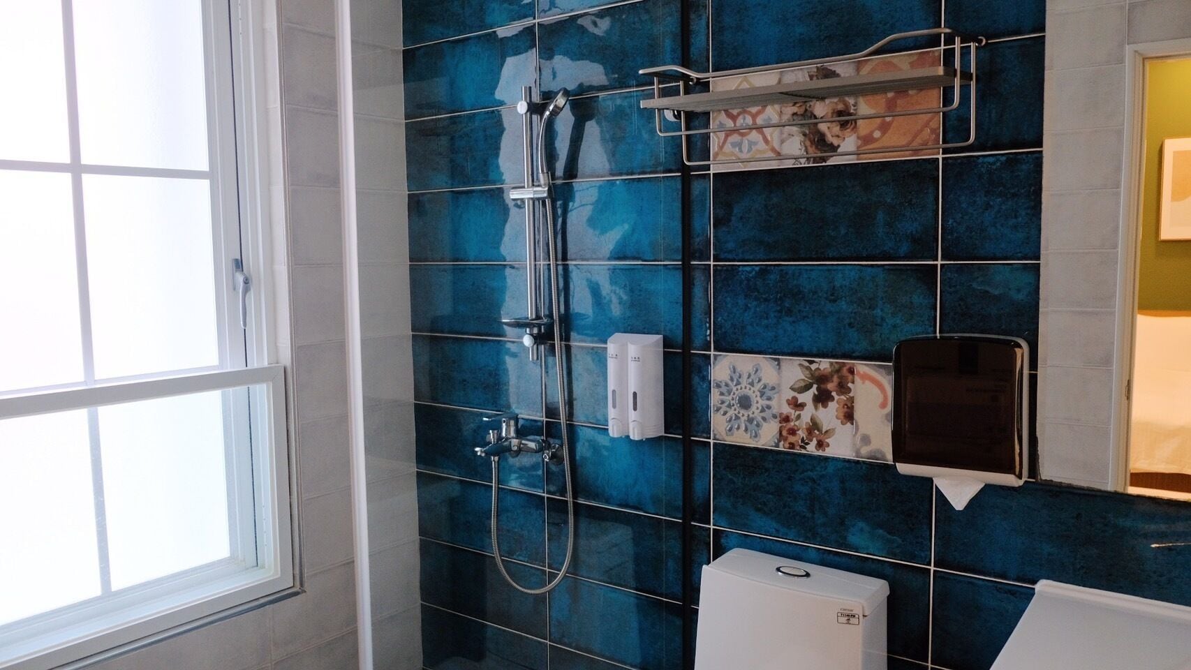 Un baño con ducha, inodoro y ventana.