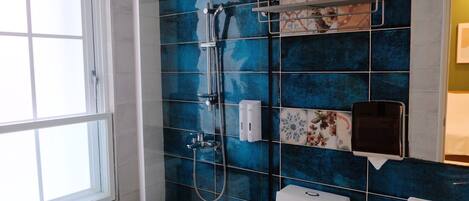 Un baño con ducha, inodoro y ventana.