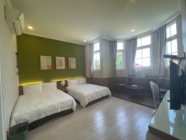 A hotel room with two beds, a desk, a chair, and a television.
