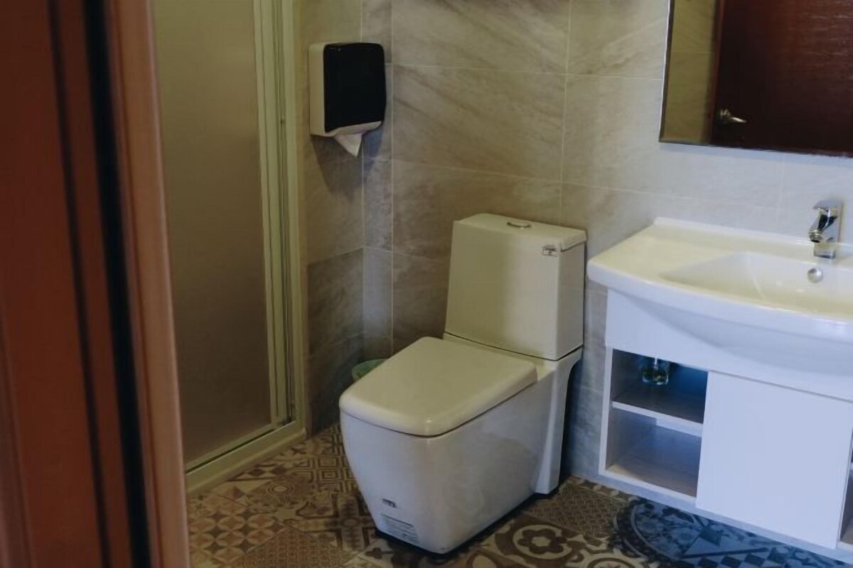 Un baño con inodoro, lavamanos y secamanos.