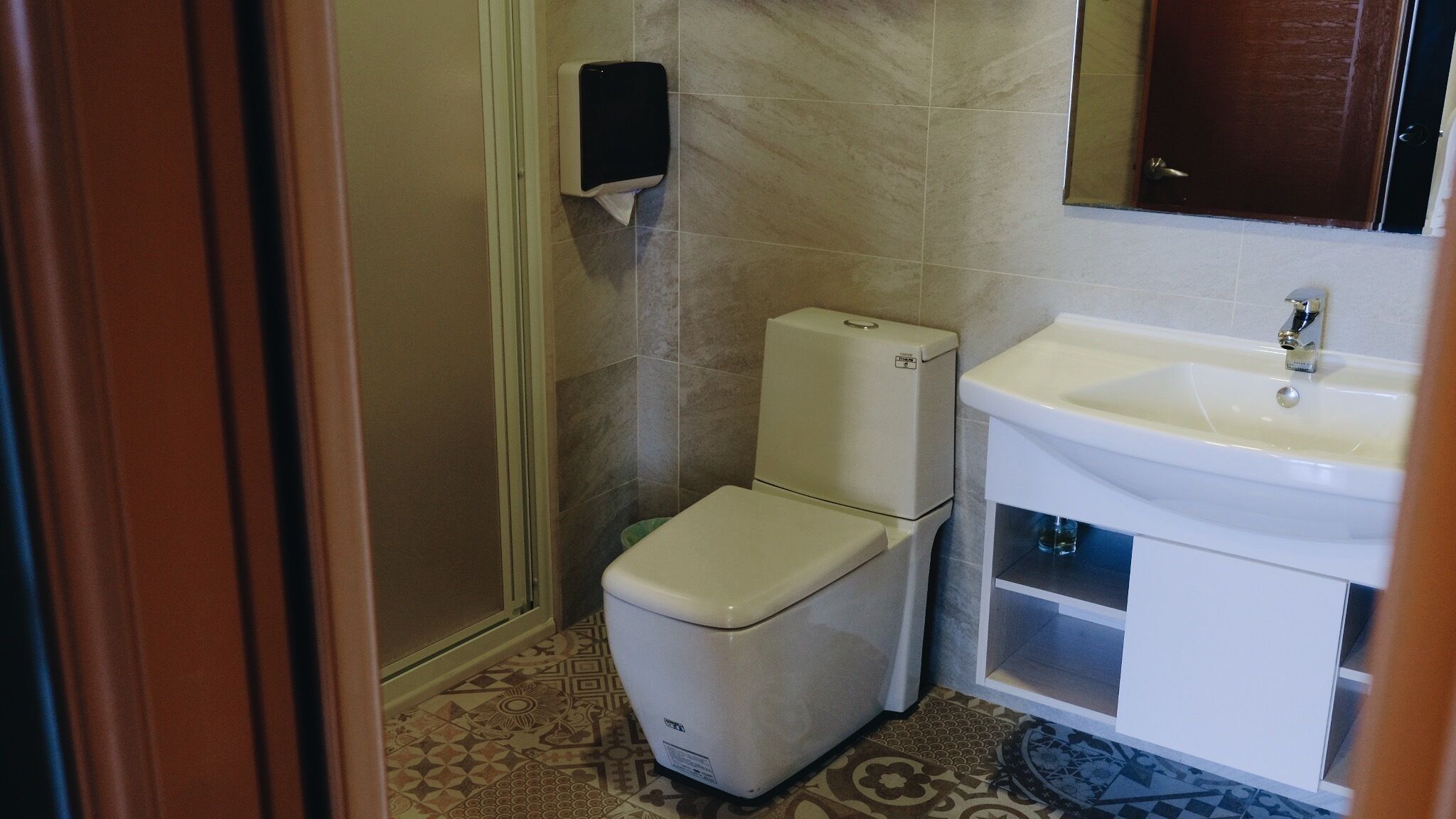 A small bathroom with a toilet, a sink, and a hand dryer.