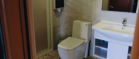 A small bathroom with a toilet, a sink, and a hand dryer.