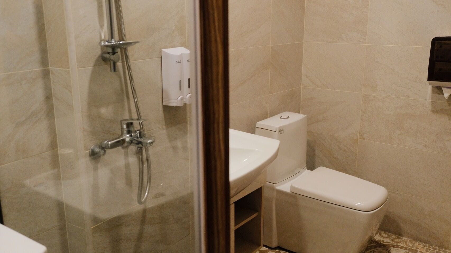 A bathroom with a glass-enclosed shower, a white sink, and a toilet.