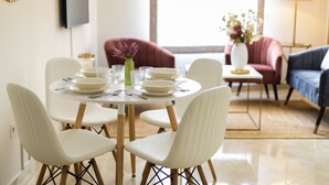 Un coin repas avec une table ronde, des chaises blanches et un vase rempli de fleurs.