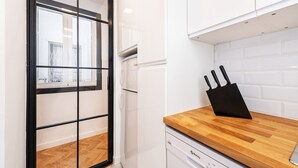 A modern kitchen with a wooden countertop, a black knife block, and a dishwasher.