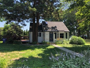 Une maison de plain-pied avec un porche à l’avant, un grand arbre devant et une pelouse bien entretenue.