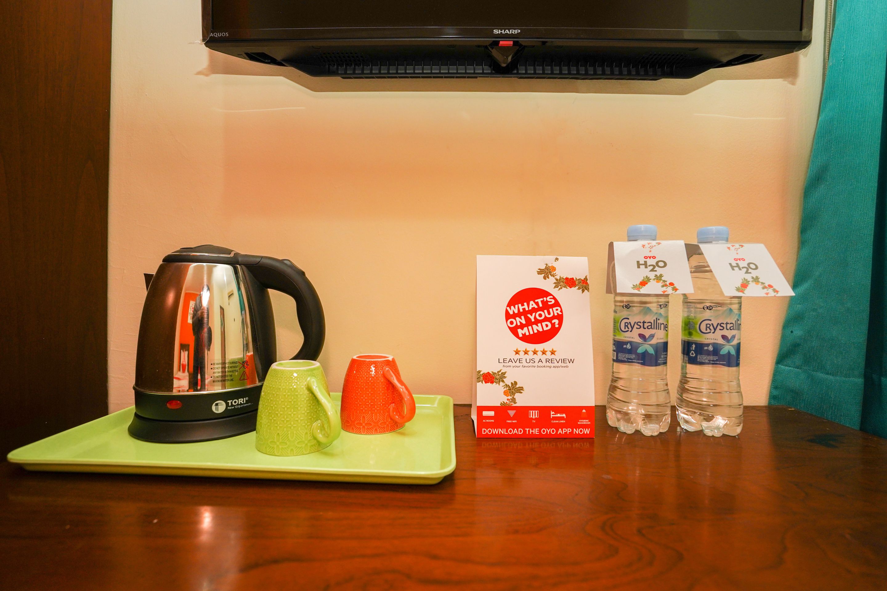 A kitchen area with a kettle, two mugs, a tray, and two water bottles on a table.
