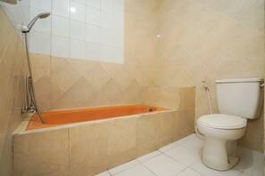 Een badkamer met een bad, toilet en douche.