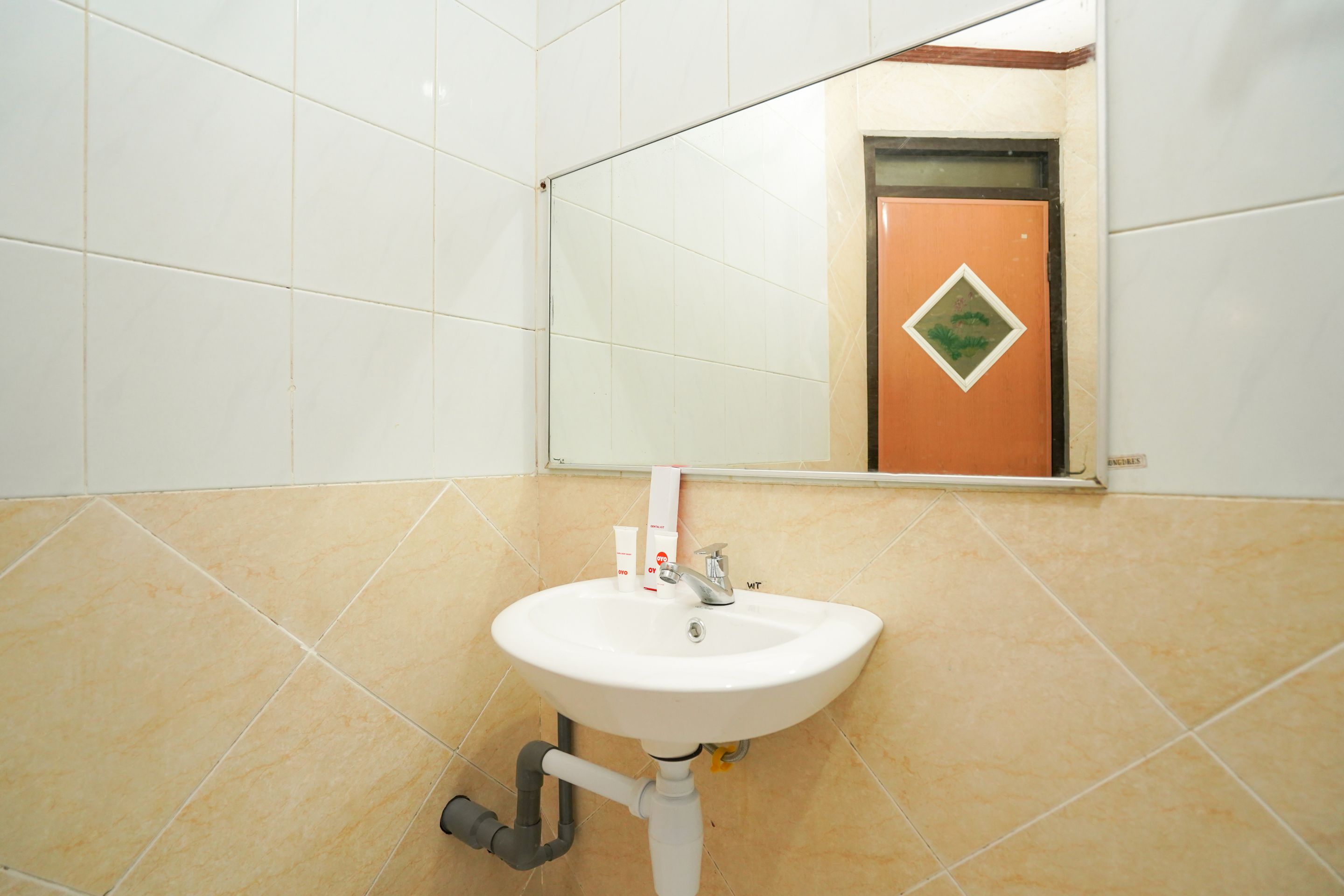 A bathroom with a white sink, a mirror, and a door with a green diamond-shaped decoration.