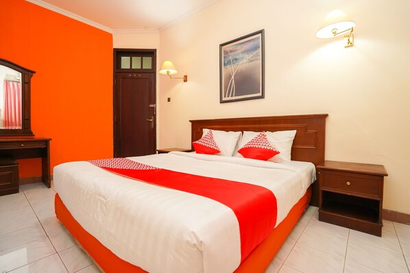 Een hotelkamer met een groot bed, een houten nachtkastje, een bureau en een deur.