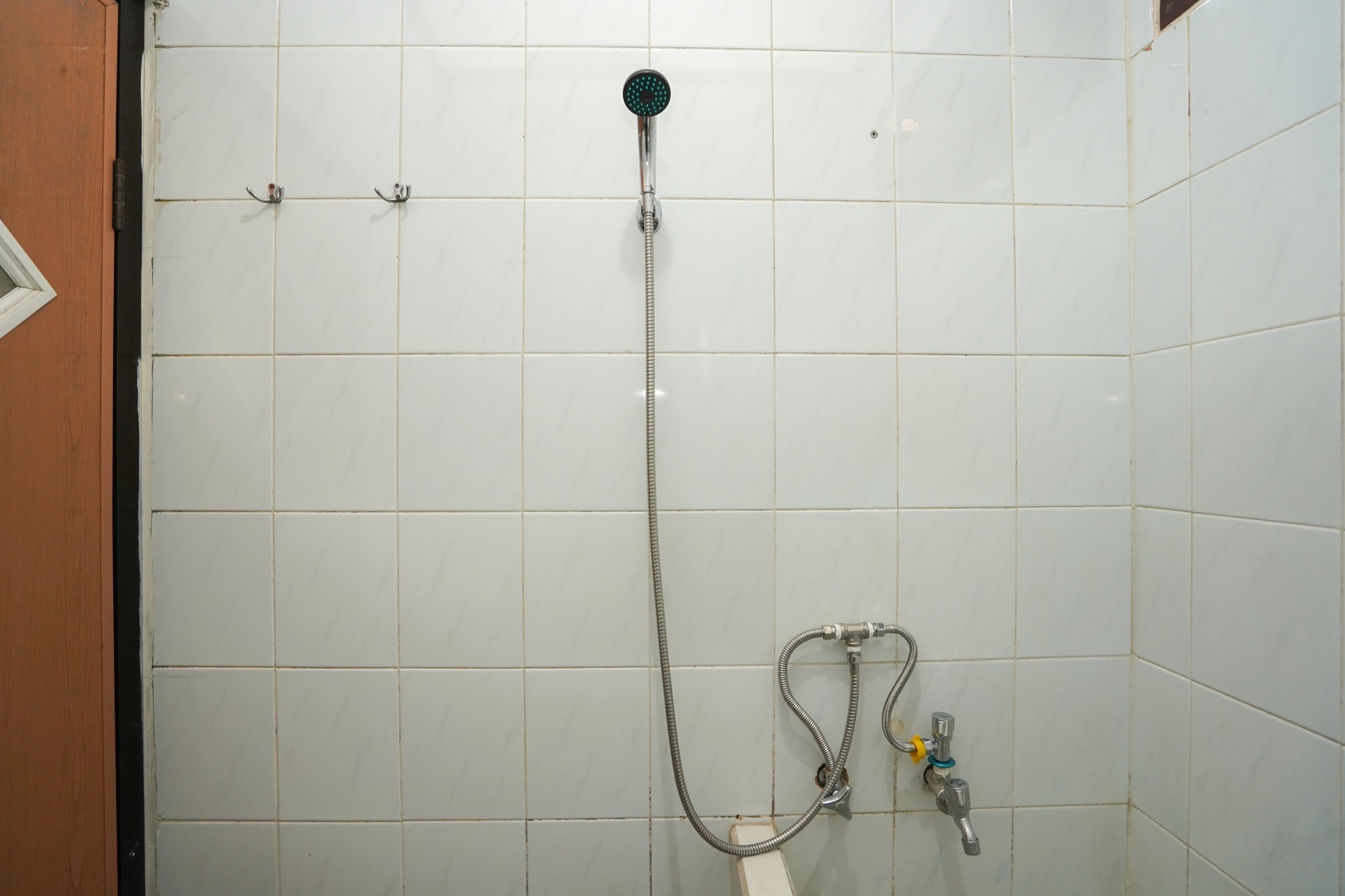 A shower with a handheld showerhead and a handheld faucet.