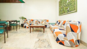Ein Wohnzimmer mit einer Couch, Sesseln, einem Couchtisch und einem Bild an der Wand.