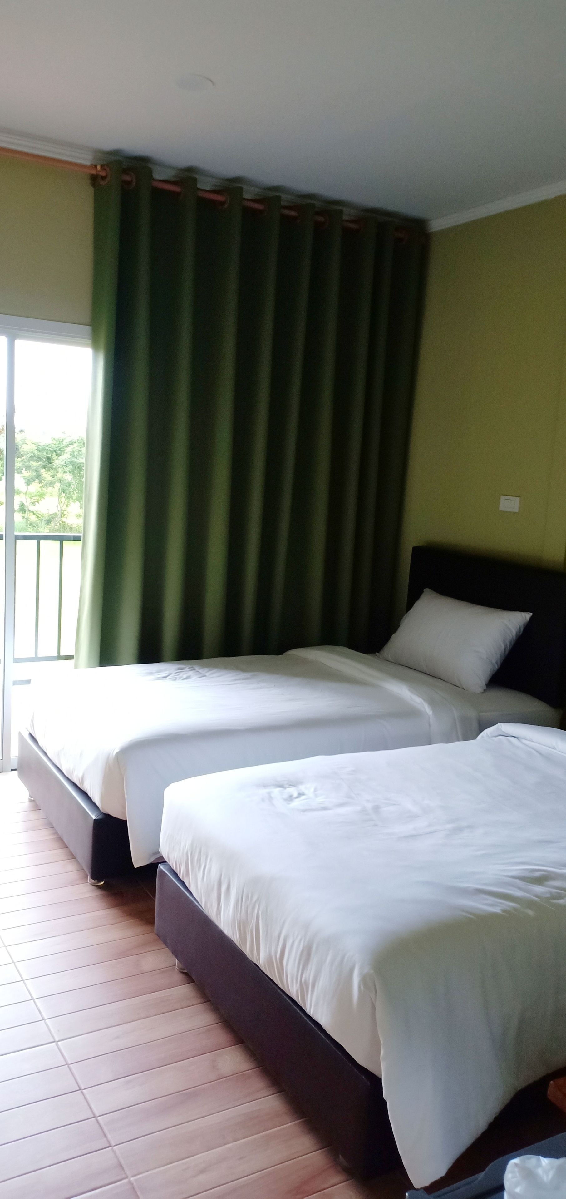 Ein Hotelzimmer mit zwei Betten, einem Balkon und einem grünen Vorhang.