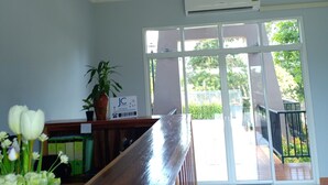 A reception area with a wooden reception desk, a potted plant, and a sign on the wall. - JC Resort (Trakan Phuet Phon)