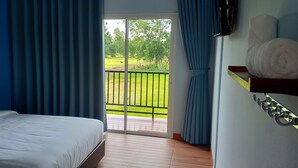 A bedroom with a bed, a view of a green landscape through a sliding door, and a metal hook on the wall. - JC Resort (Trakan Phuet Phon)