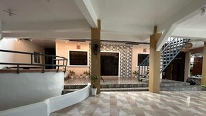 A spacious indoor area with a tiled floor, a staircase, and a balcony with railings. - Evangeline Garden and Lodge (Silang)