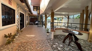 A spacious indoor area with a tiled floor, a staircase, and a seating area with a table and chairs. - Evangeline Garden and Lodge (Silang)